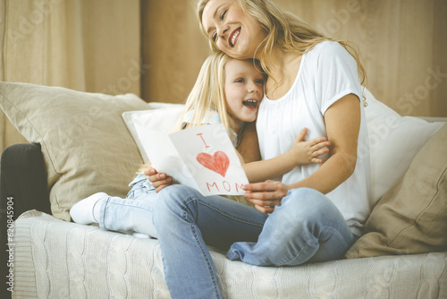 Happy mother day. Child daughter congratulates mom and gives her postcard with heart drawing. Family and childhood concepts