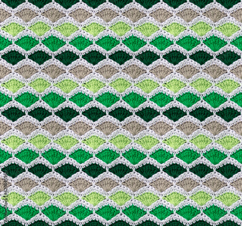 Seamless knitted texture. The pattern in the form of honeycombs is crocheted from colored cotton yarn. Shell design.