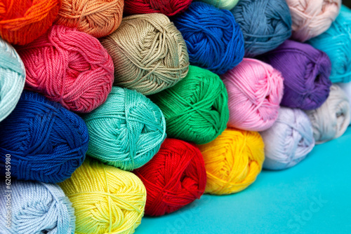 Multi-colored skeins of cotton yarn stacked on top of each other in perspective. Materials for knitting. Textile industry. Arranged balls of yarn. Small depth of field.