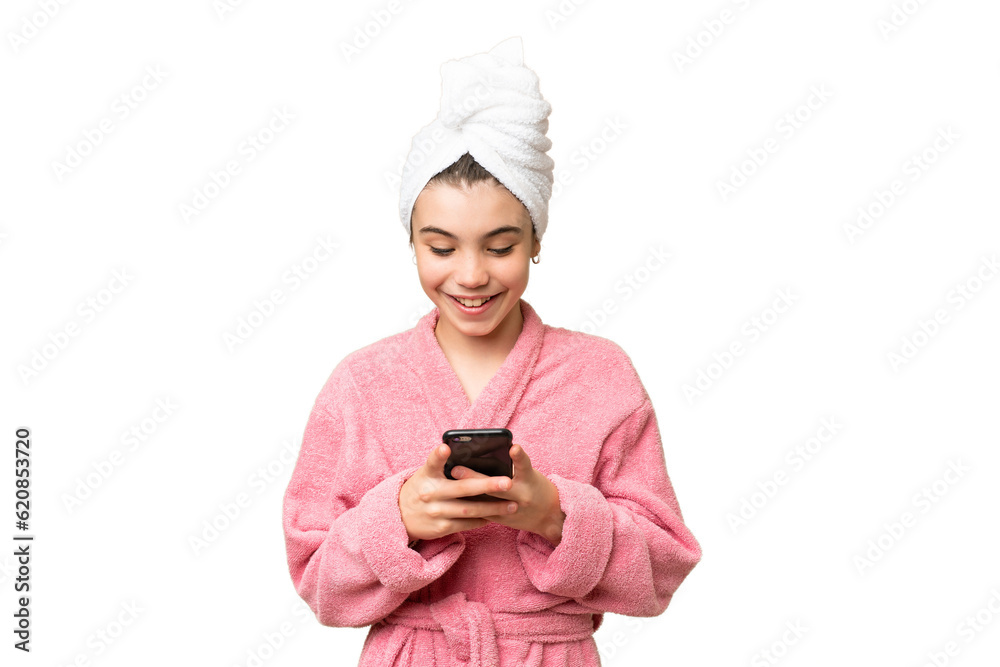 Little girl in a bathrobe over isolated chroma key background sending a message with the mobile Little girl in a bathrobe over isolated chroma key background sending a message with the mobile