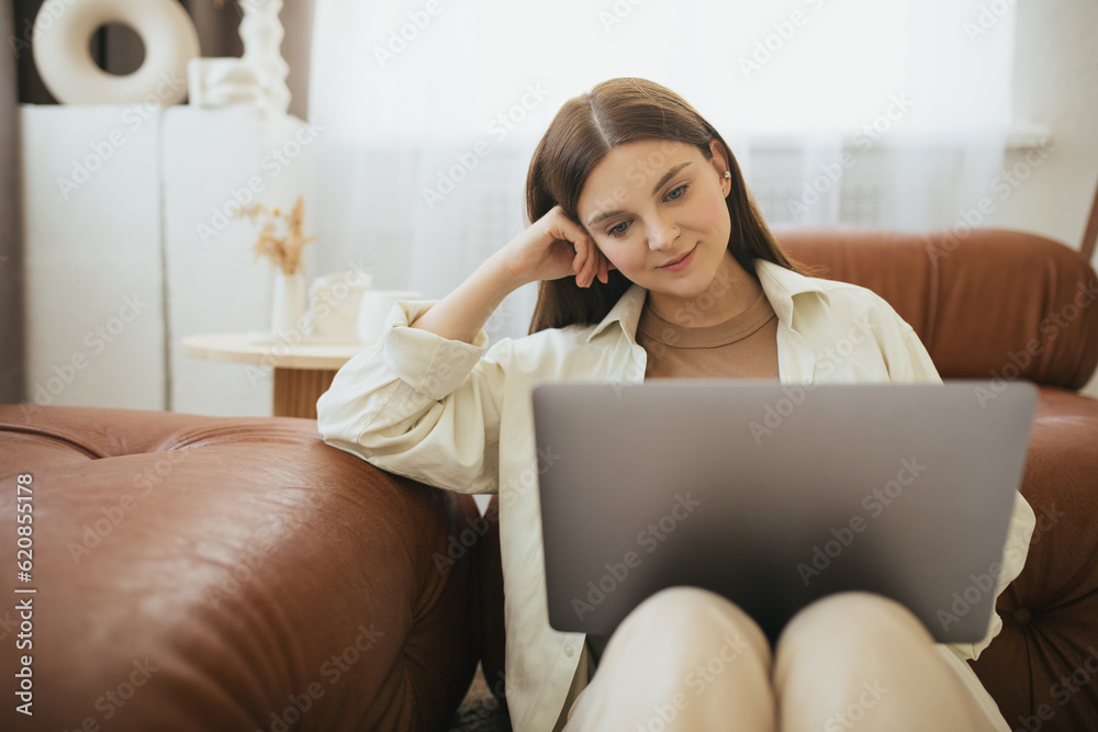 Young woman freelancer working online using laptop, sitting in a cozy living room Young woman freelancer working online using laptop, sitting in a cozy living room
