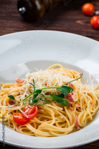 Spaghetti with bacon, cherry tomatoes, parmesan cheese and herbs, closeup.
