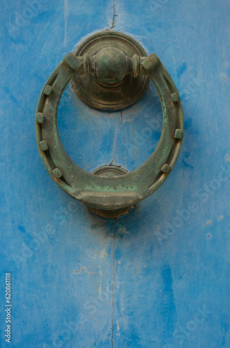 Door knocker shaped like a horseshoe on a blue wooden door.