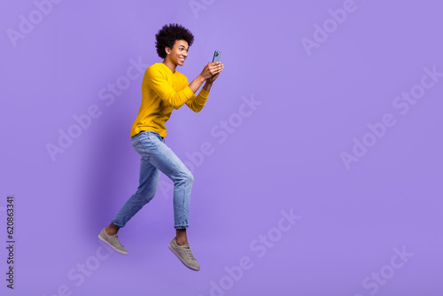 Full length photo of satisfied guy wear stylish sweatshirt look at smartphone fast internet speed isolated on violet color background