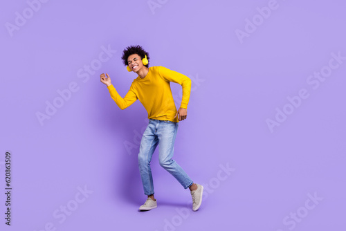 Full size photo of good mood handsome guy dressed yellow long sleeve headphones dancing enjoy music isolated on purple color background