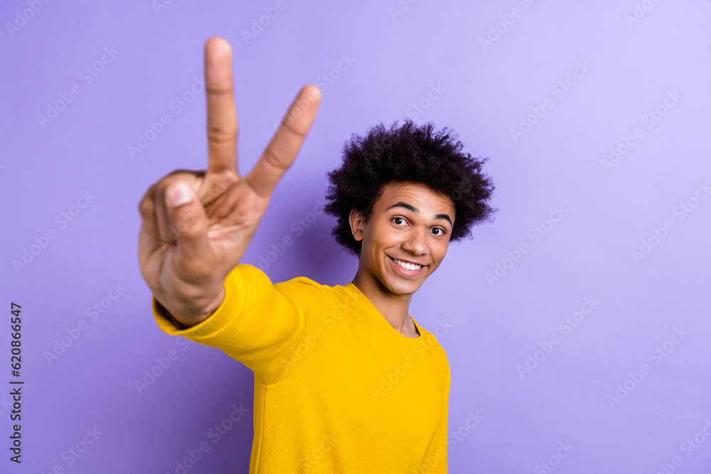 Portrait of positive nice man beaming smile good mood arm fingers demonstrate v-sign isolated on purple color background Portrait of positive nice man beaming smile good mood arm fingers demonstrate v-sign isolated on purple color background