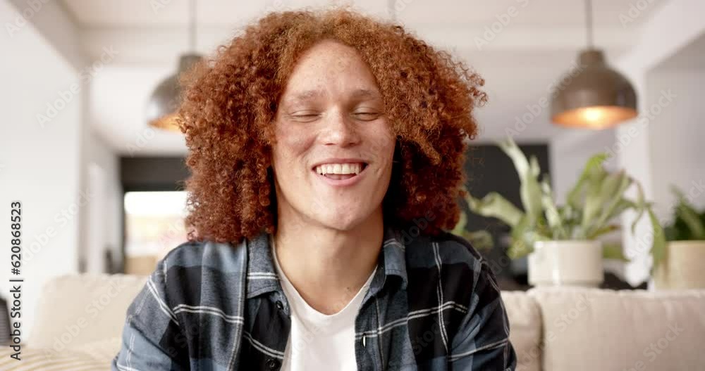Happy biracial man making video call, sitting on sofa talking in living room, slow motion Happy biracial man making video call, sitting on sofa talking in living room, slow motion