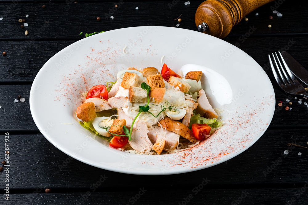 Caesar salad with chicken, parmesan cheese, eggs, lettuce, tomatoes, croutons on a dark table, Italian cuisine. Caesar salad with chicken, parmesan cheese, eggs, lettuce, tomatoes, croutons on a dark table, Italian cuisine.
