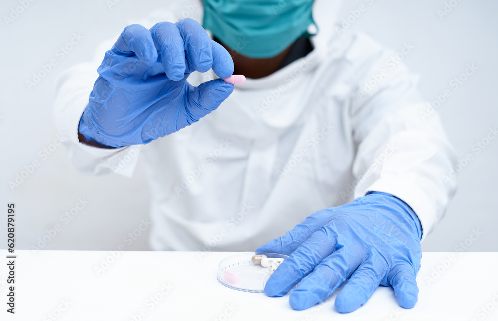 Fototapeta premium Doctor holding a capsule pill with hand in pharmaceutical research laboratory