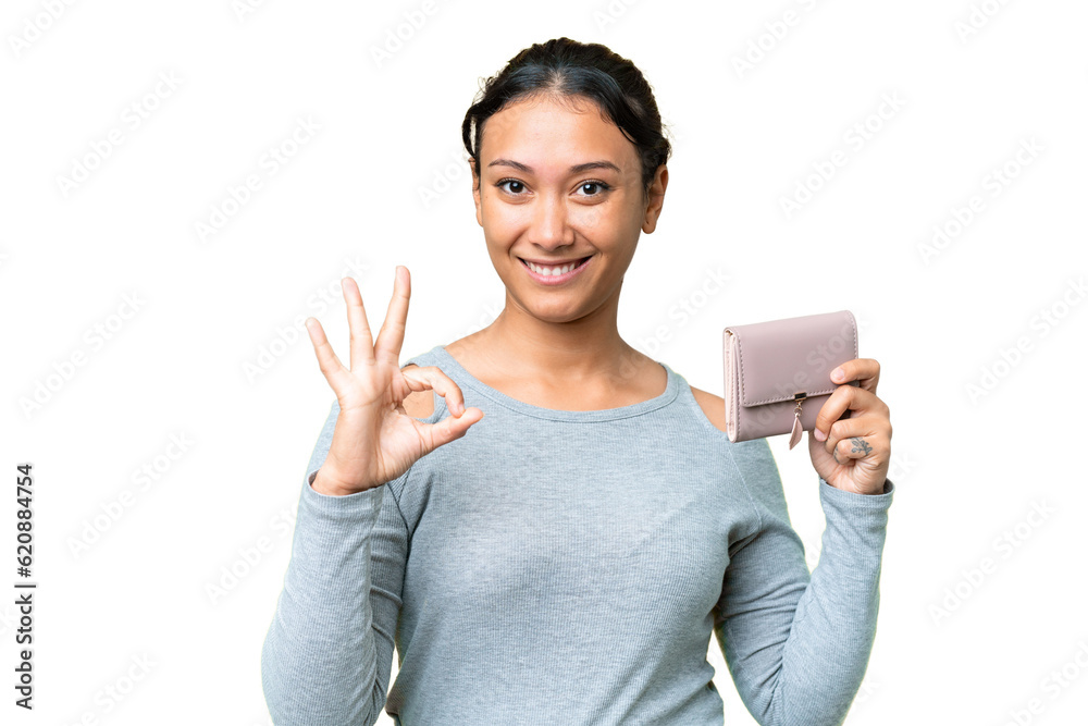 Young Uruguayan woman holding a wallet over isolated chroma key background showing ok sign with fingers Young Uruguayan woman holding a wallet over isolated chroma key background showing ok sign with fingers