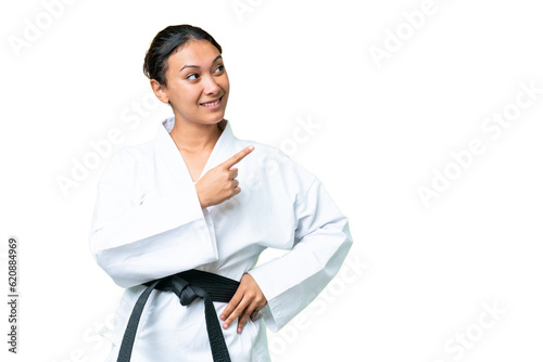 Young Uruguayan woman over isolated chroma key background doing karate and pointing to the lateral