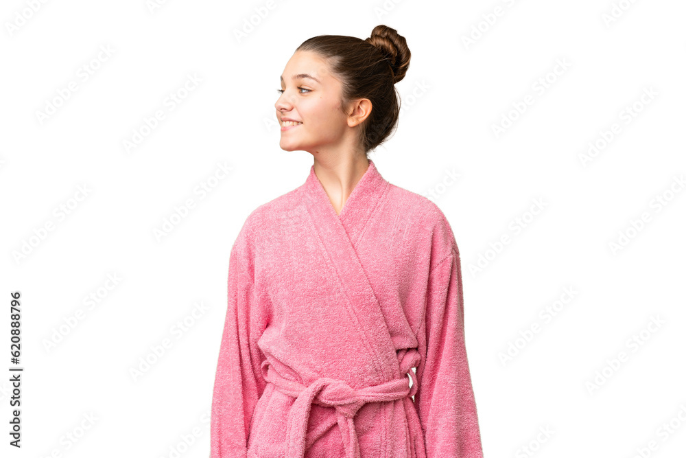 Teenager girl in a bathrobe over isolated chroma key background looking side Teenager girl in a bathrobe over isolated chroma key background looking side