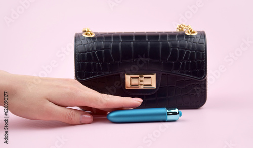 Fotografija A blue bullet-dildo in a small black purse on a light background with copyspace text for a sex shop