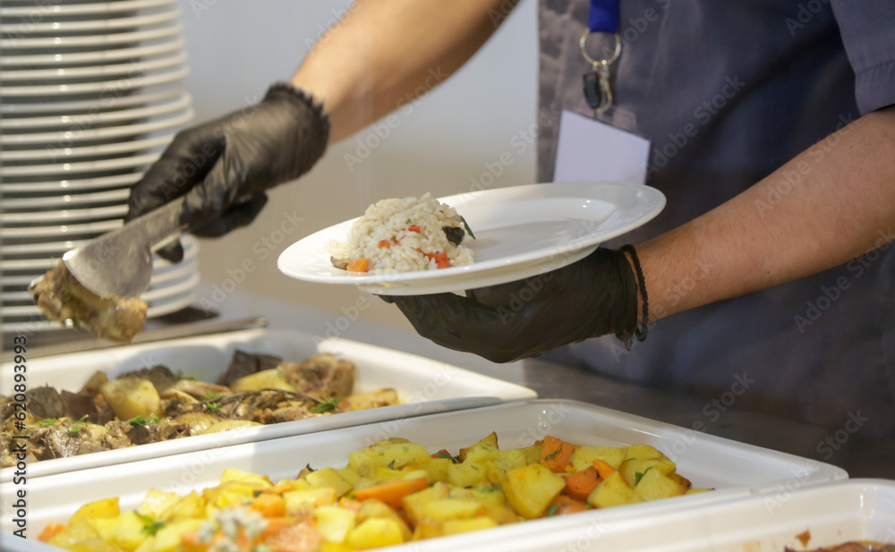 Buffet style service Canteen worker at serving line putting food on