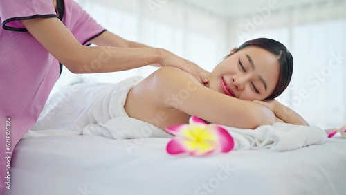 Therapist massaging back of asian woman in totwel lying on bed relaxing during spa massage. Beautiful young asian woman lying on spa bed and relaxing while massaging back. Body relaxation concept