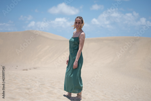 Blond young girl with green dress on the beach dunes