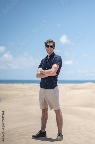 Blond young boy with crossed arms sunglasses on the beach dunes
