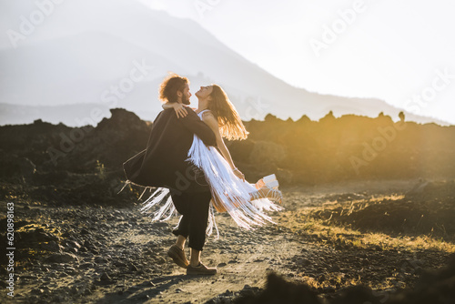  A beautiful, stylish couple, lovers, a man and a woman, in beautiful clothes posing, spinning, hugging against the background of the mountains.