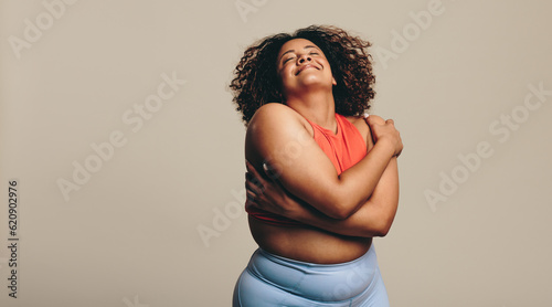 Body confident young woman embracing her body in a studio, expressing self-love