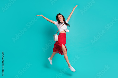 Fototapeta Naklejka Na Ścianę i Meble -  Photo of charming shiny lady dressed white crop top jumping high having fun isolated turquoise color background
