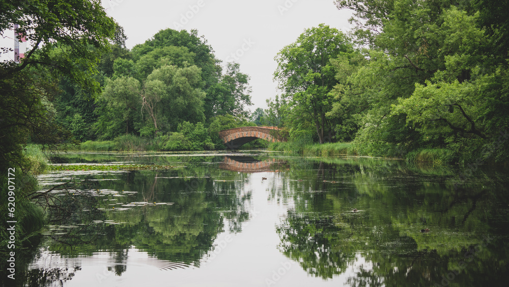 Lake of a park with a bridge making a beautiful water reflection on a cloudy day Lake of a park with a bridge making a beautiful water reflection on a cloudy day