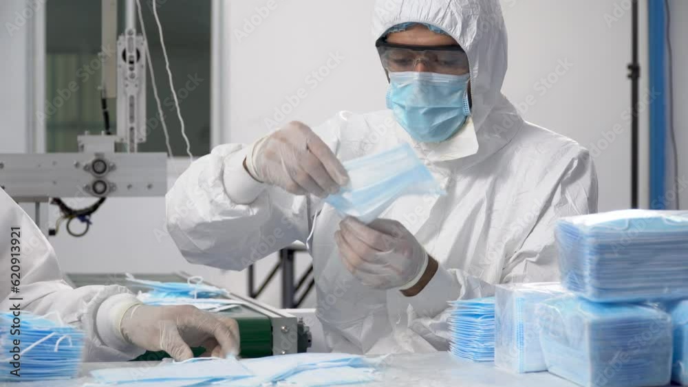 group of worker in ppe suit inspecting quality control and counting surgical face mask in production line at industry factory. group of worker in ppe suit inspecting quality control and counting surgical face mask in production line at industry factory.