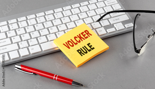 VOLCKER RULE text on a sticky with keyboard, pen glasses on grey background photo