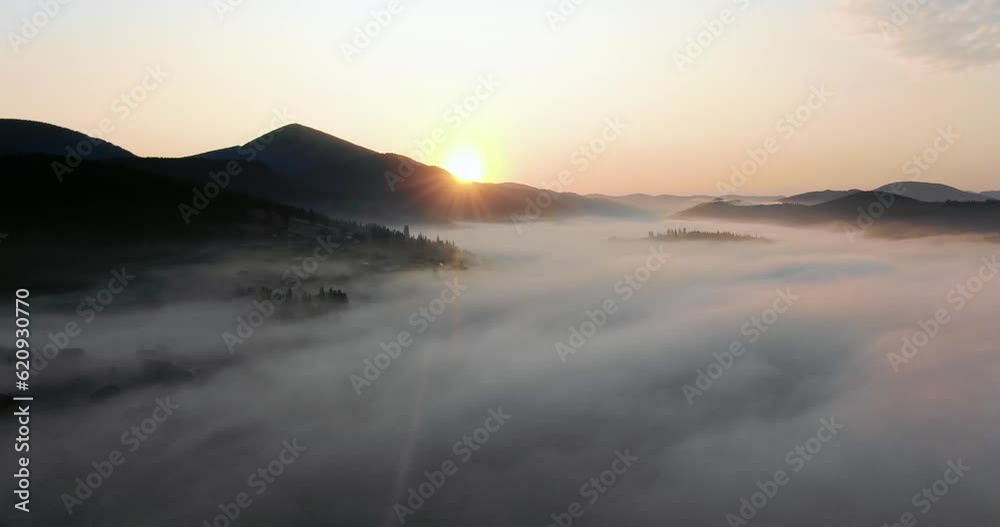 Aerial survey of mountains covered with green forests and spruce with fog or smoke between them in summer weather. The relief surface of the Earth with forests, meadows and small villages, settlements Aerial survey of mountains covered with green forests and spruce with fog or smoke between them in summer weather. The relief surface of the Earth with forests, meadows and small villages, settlements