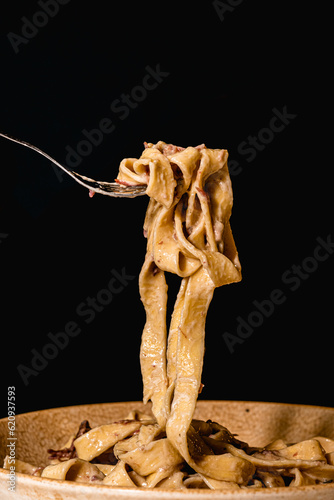pasta italiana en fondo negro y enrollada con tenedor