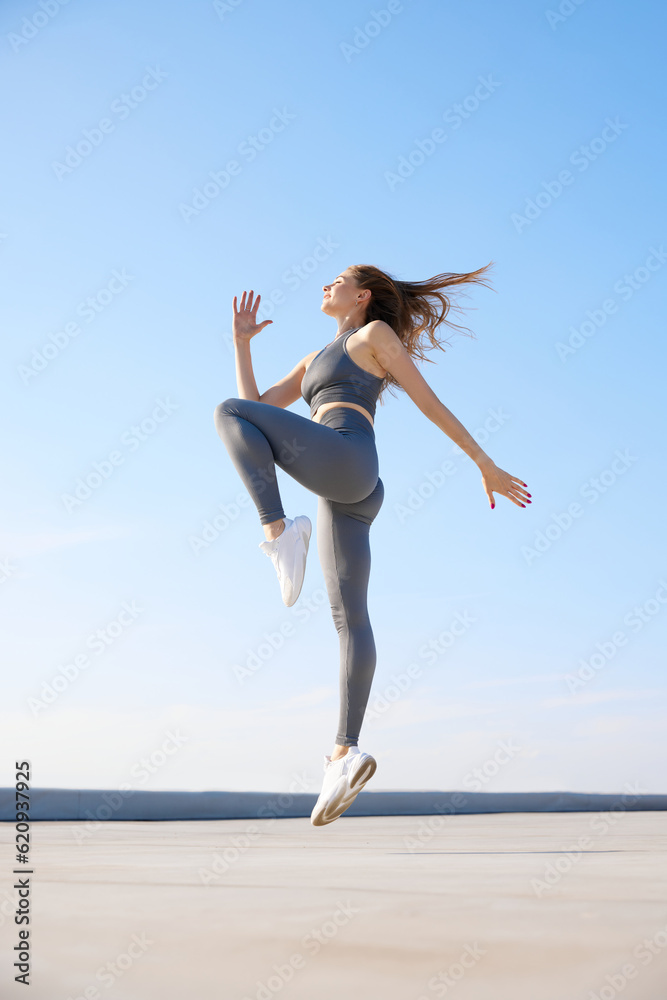 Young woman with slim, fit body in comfortable sportswear training outdoors on warm summer day. Stretching Young woman with slim, fit body in comfortable sportswear training outdoors on warm summer day. Stretching