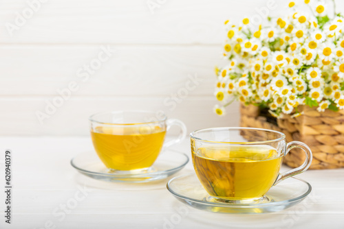 Chamomile herbal tea with flower buds, honey and lemon on a white wooden table and a bouquet of chamomile. Useful herbal, soothing drinks and natural healer concept. Immunity tea.Close up. Copy space.