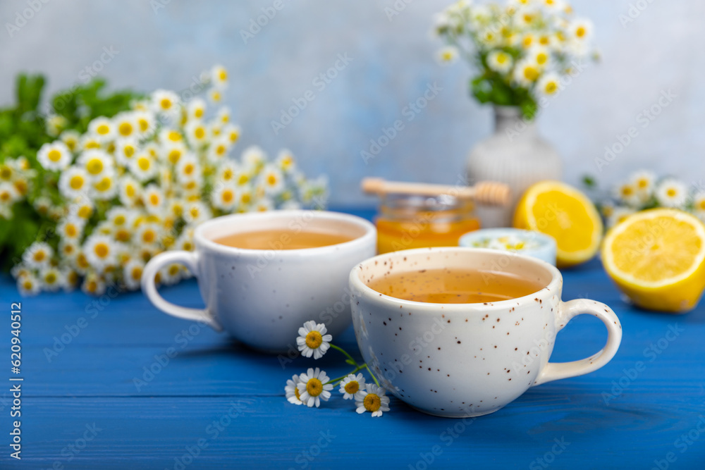Chamomile herbal tea with flower buds on a blue wooden table and a bouquet of chamomile. Useful herbal, soothing drinks and natural healer concept. Immunity tea.Close up. Copy space. Chamomile herbal tea with flower buds on a blue wooden table and a bouquet of chamomile. Useful herbal, soothing drinks and natural healer concept. Immunity tea.Close up. Copy space.