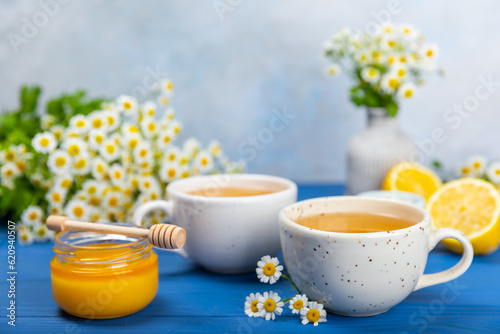 Fototapeta Naklejka Na Ścianę i Meble -  Chamomile herbal tea with flower buds on a blue wooden table and a bouquet of chamomile. Useful herbal, soothing drinks and natural healer concept. Immunity tea.Close up. Copy space.