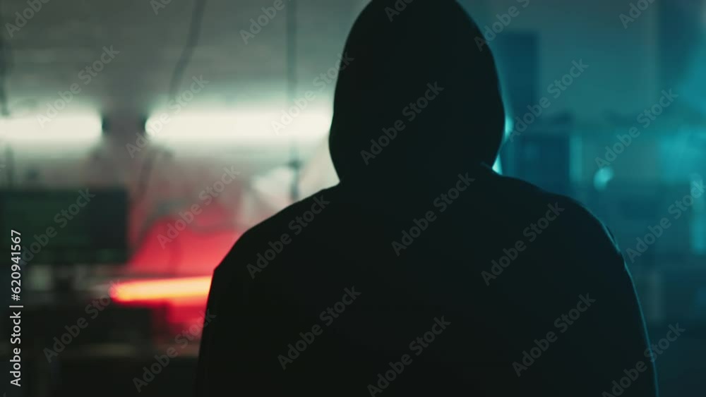 Mysterious cyber security hacker in hoodie in headquarter with computers