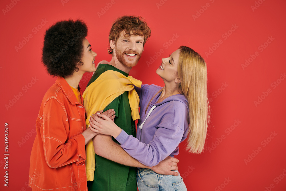 polygamy concept, interracial lovers showing hugging each other on coral background, cultural diversity, polyamorous, happy multiethnic people, looking at camera, open relationship polygamy concept, interracial lovers showing hugging each other on coral background, cultural diversity, polyamorous, happy multiethnic people, looking at camera, open relationship