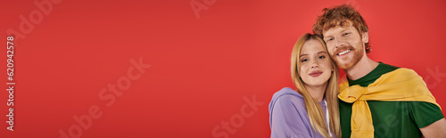Photography portrait of young couple looking at camera on coral background, vibrant colors,