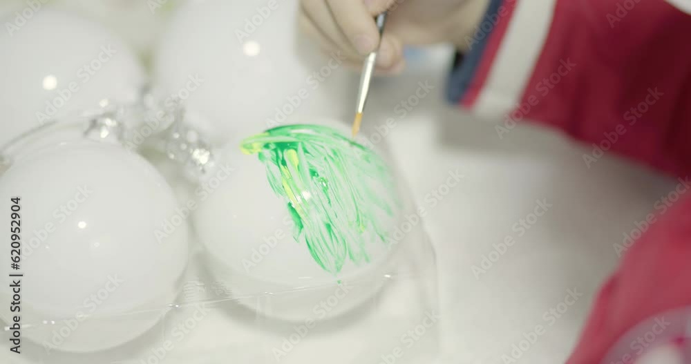 Boy making custom Christmas decorations. Painting green tree on white crystal or plastic ball. Boy making custom Christmas decorations. Painting green tree on white crystal or plastic ball.