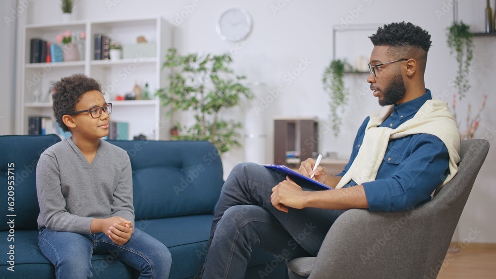 Schoolboy talking to a high-qualified psychologist in his office, mental health assessment