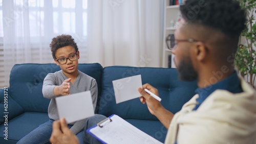African American school psychologist conducting psychological assessment of a boy, child therapy