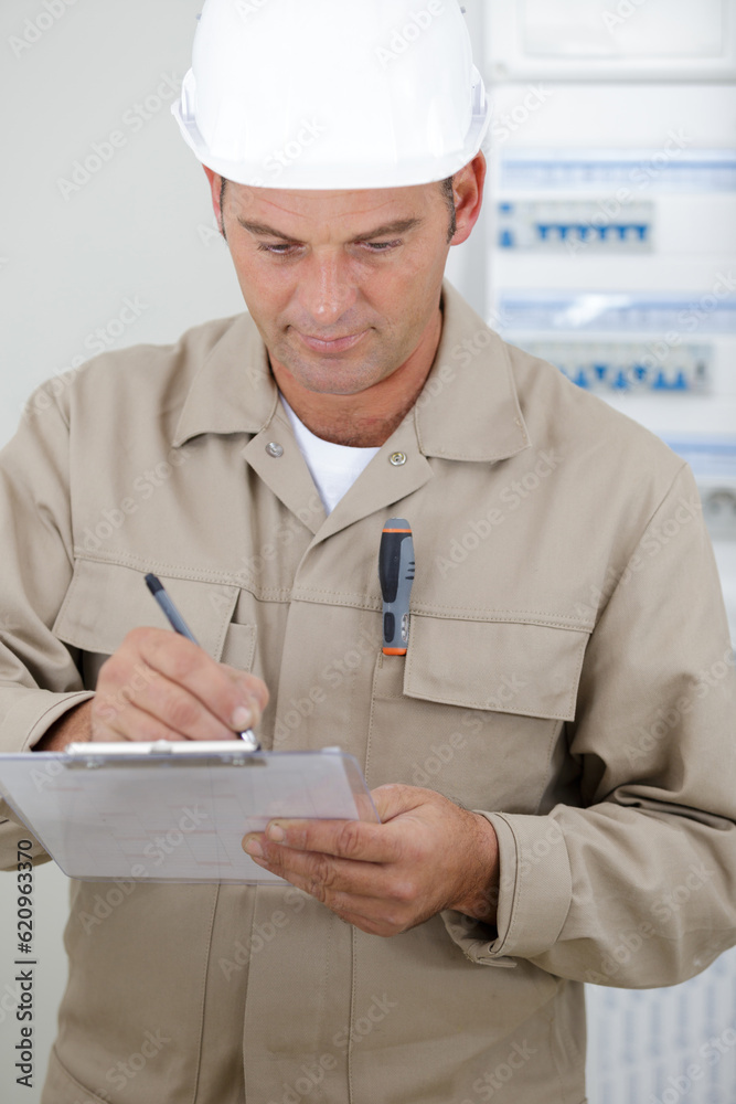 portrait of electrician standing next to fuseboard portrait of electrician standing next to fuseboard
