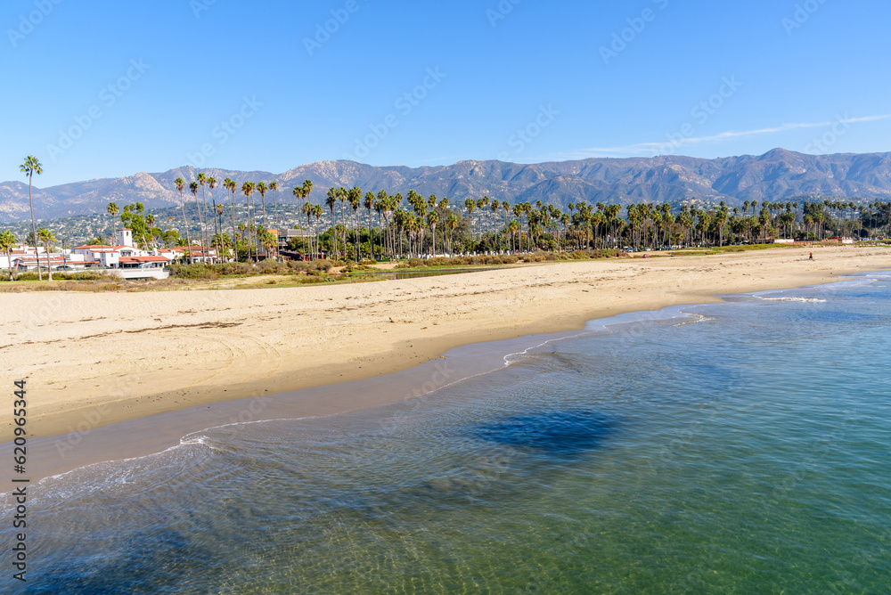 View of the golden shore of Santa Barbara lined with palm trees with the mountains in background