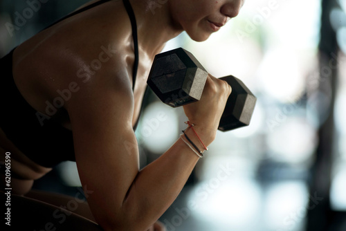 Foto Fitness girl lifting dumbbell weights at the gym, doing exercises with dumbbell,