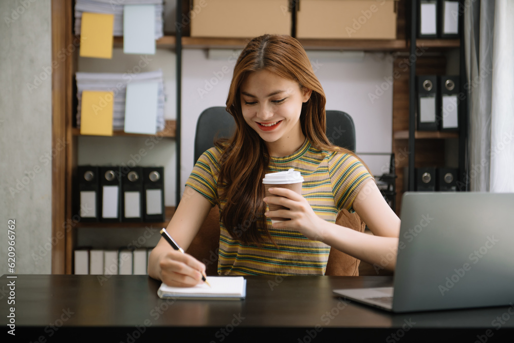 Young beautiful woman typing on tablet and laptop while sitting at the working wooden table office. Young beautiful woman typing on tablet and laptop while sitting at the working wooden table office.
