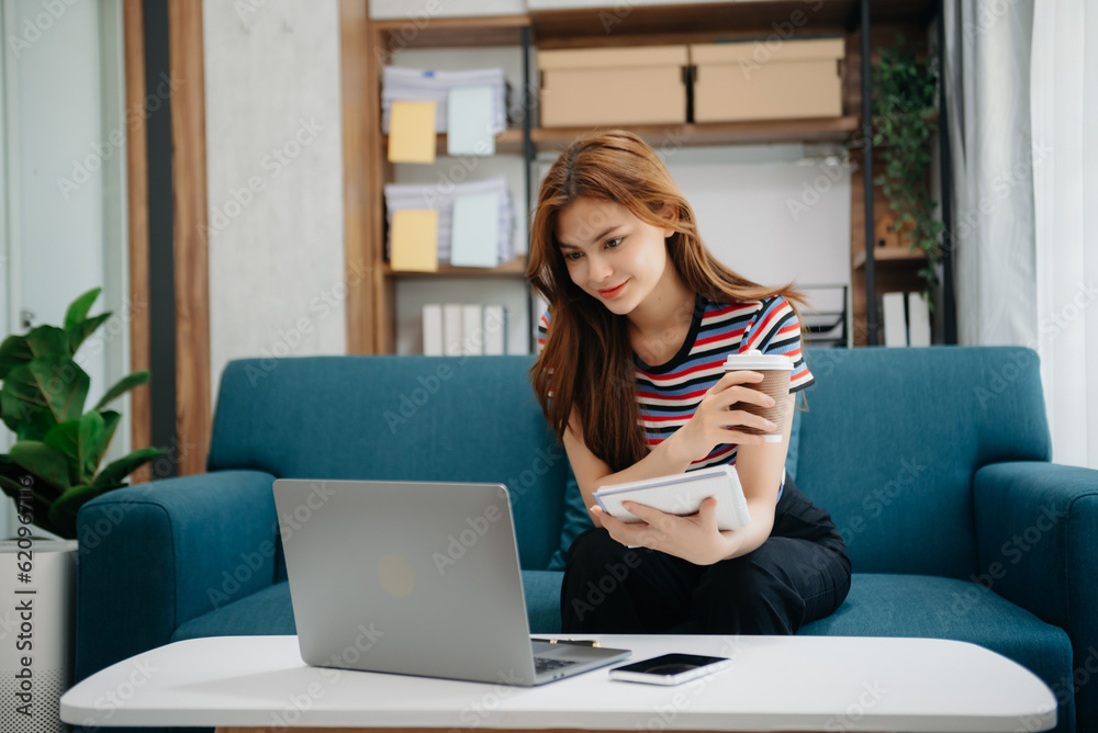 Confident beautiful Asian businesswoman typing laptop computer and digital tablet on sofa at office Confident beautiful Asian businesswoman typing laptop computer and digital tablet on sofa at office