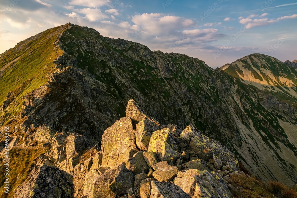 Obraz premium Summer hiking in the mountains with massive rocks, dramatic skies and majestic mountains. Mountain sunset in Slovakia mountain - Rohace, Mountain hiking holiday Western Tatras.