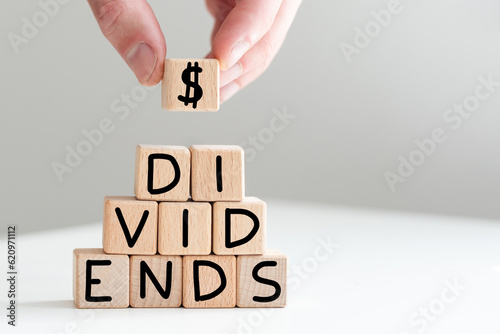DIVIDEND word on cubes with a chest of money against a dark background. Business and finance concept