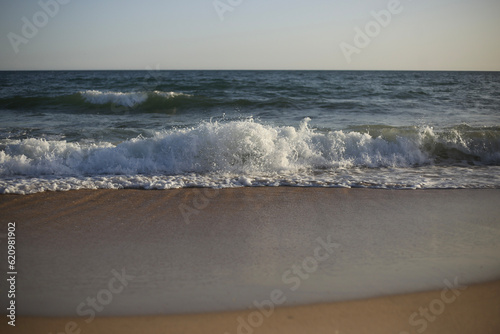 Ondas do mar em um belo entardecer no Algarve, Portugal. A praia é o destino ideal para aproveitar as férias de verão, desfrutando da serenidade e beleza natural que o lugar oferece. photo