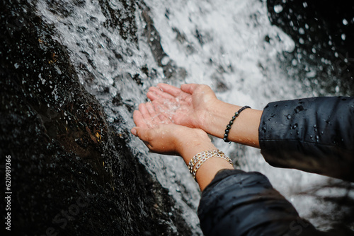 Bilde på lerret woman's hands touching the water of a cold waterfall in the andean mountains