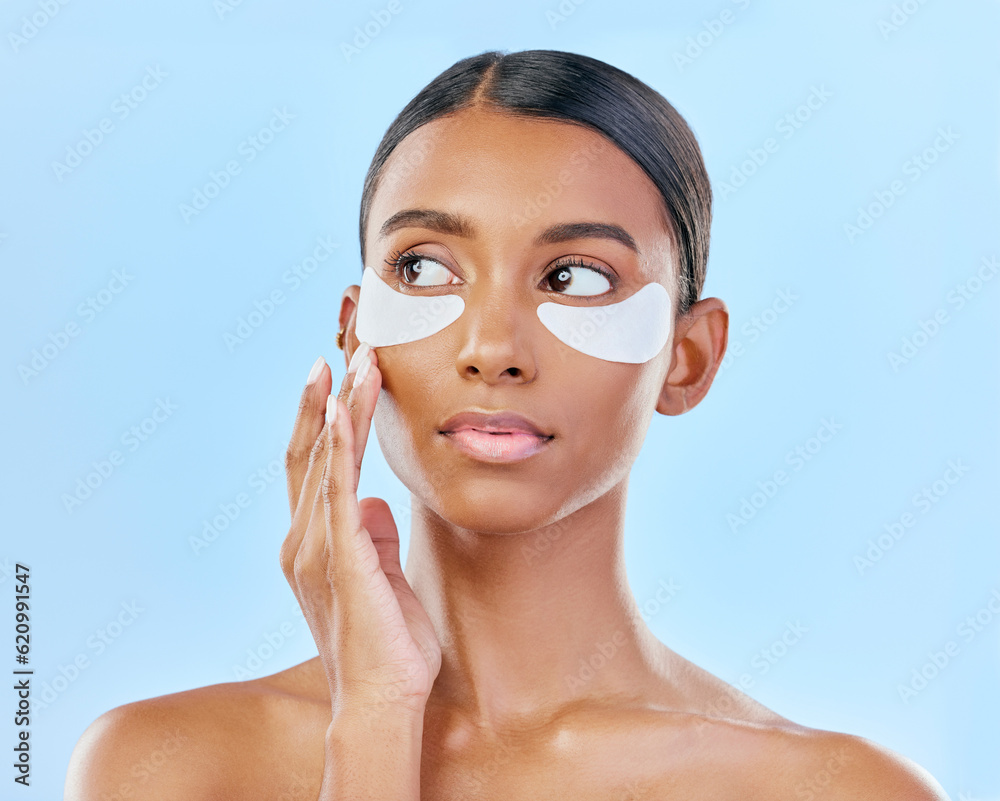 Face, eye patch and beauty of a woman with natural skin glow on a blue background. Dermatology, collagen mask and cosmetics of Indian female model for facial shine, wellness or self care in studio