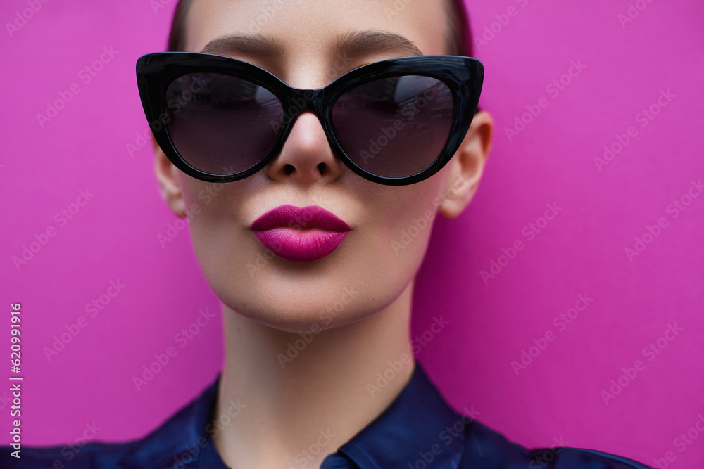 Sunglasses fashion model portrait. Classic style glasses shape. Pink lips blowing kiss. Beautiful woman in cat eyes black glasses again pink background Sunglasses fashion model portrait. Classic style glasses shape. Pink lips blowing kiss. Beautiful woman in cat eyes black glasses again pink background